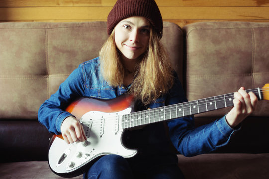 Young woman playing  electric guitar. Music concept. Home atmosphere on background.