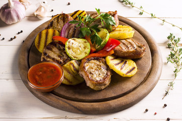 Grilled vegetables with meat and sauce on a wooden round Board