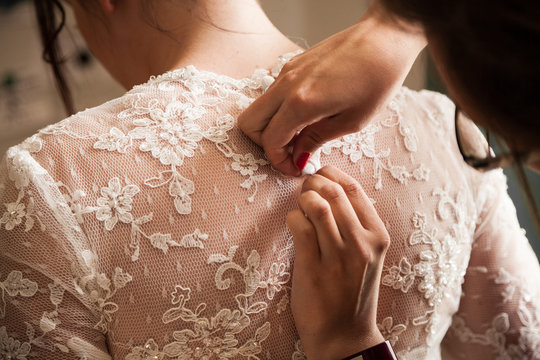 Dos de la mari&eacute;e pendant qu'elle se fait boutonner sa robe