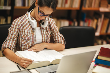 Young female student study in the school library.She reading a book.