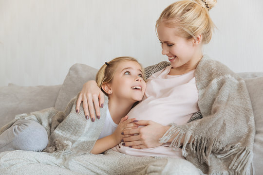 happy daughter touching pregnant mother belly