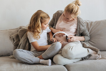 pregnant mother and daughter giving to listen music to embryo