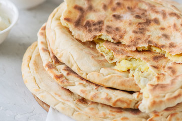 Mashed potato and sheep cheese filling flatbread on a white stone background.
