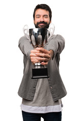 Handsome man with beard holding a trophy on white background