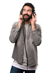 Handsome man with beard listening music on white background