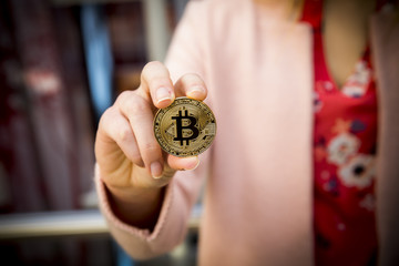 golden bitcoin in a woman's hands
