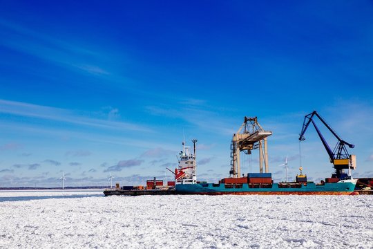 Industrial port with containers in winter, vessel loading in port of Finland
