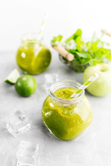 Green healty drink in mason jar with green apple, mint, lime and melting ice cubes on grey background. Vegetarian food concept. Detox. Text space