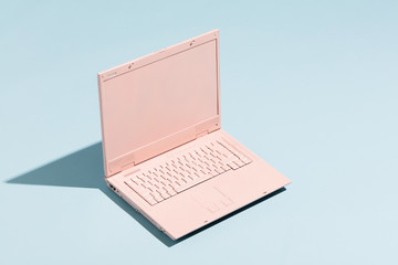 Retro pink laptop on a pastel blue background.