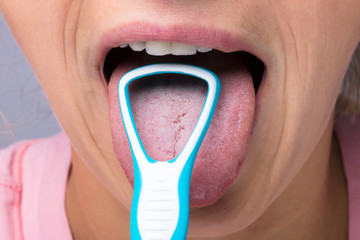 Woman Cleaning Tongue With Cleaner