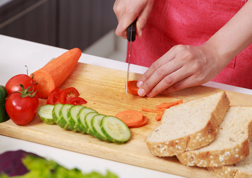 hand cutting carrot on board in kitchen room