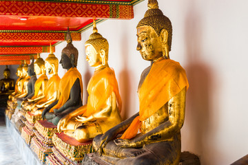 beautiful golden Buddha statues sitting in a row in the temple of Bangkok, Thailand