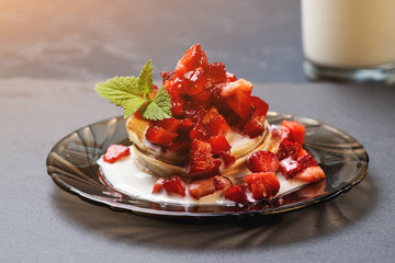 Stack of pancakes with ripe strawberries and pouring by jogurt.