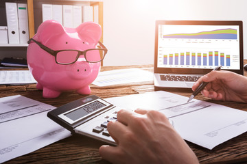 Close-up Of A Businessperson's Hand Calculating Invoice