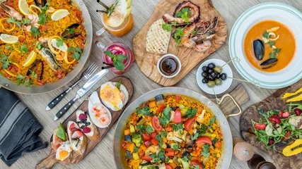 Photo sur Plexiglas Plats de repas Assorted spanish food set. Tapas, Paella, grilled seafood, olives, seafood soup, strawberry lemonade, grilled scallop on wooden table
