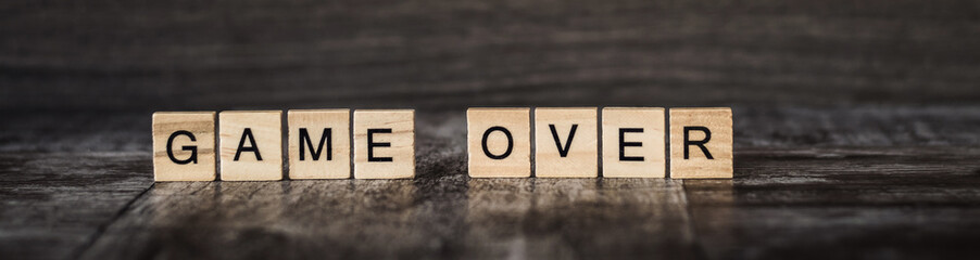 the words game over made of bright wood cubes with black letters on a dark wooden background