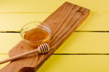 Honey in plate with wooden chopstick for honey on wooden background.