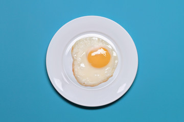 Fried Eggs In A White Plate On A Blue Background