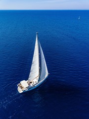 Aerial view from drone of white yacht in deep blue sea