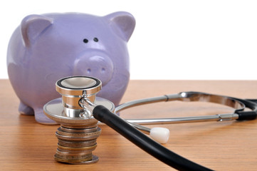 Stéthoscope posé sur une pile de pièces de monnaie à côté d'un e tirelire, cochon 