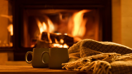 Steam from a cups with a hot cocoa on the fireplace background.  