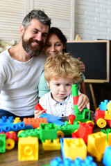 Fototapeta premium Parents watch their son with happy faces making brick constructions.