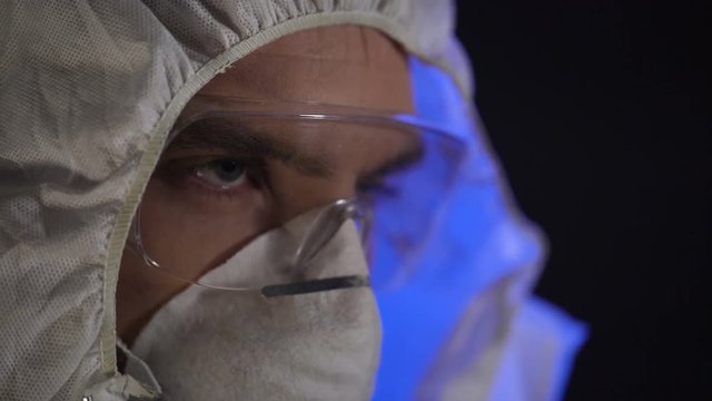 Man wearing lab costume in clandestine laboratory, illegal drug producing