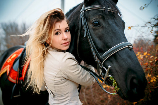 Incredibly beautiful woman with luxurious hair walks with a horse