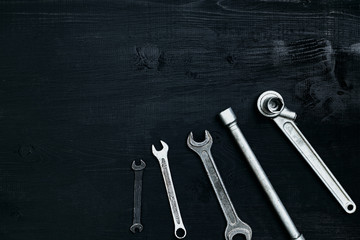 Flat lay of set of tools for car repairing such as wrenches on black wooden background. Top view.