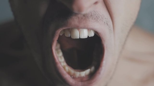Close-up mouth of angry man screaming in slow motion. Threat of violence.
