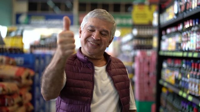 Senior Man Satisfied with Thumbs Up in Supermarket