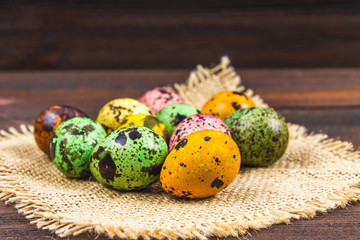 Quail multi-colored Easter eggs on a brown wooden table.