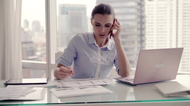 Young, busy businesswoman working by table in the office, 4K
