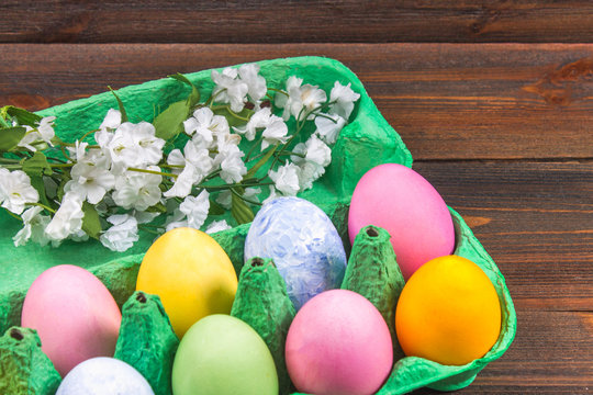 Multicolored easter eggs in a green tray on a brown wooden table.
