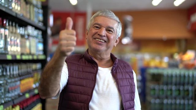 Senior Man Satisfied with Thumbs Up in Supermarket