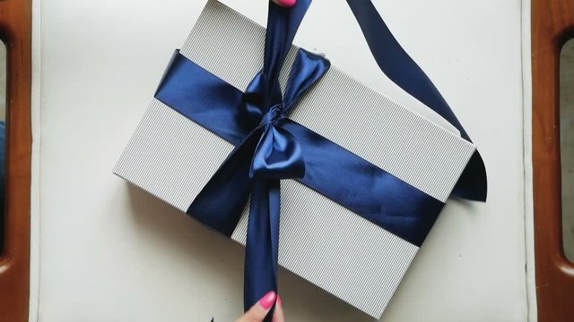 girl unties the ribbon on blue striped box of clothes