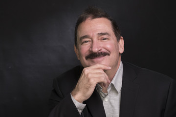Portrait of a business man with a mustache, smiling, resting chin on hand