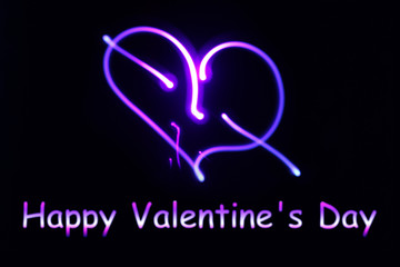 A neon glowing heart and an inscription happy Valentine's Day on a dark background