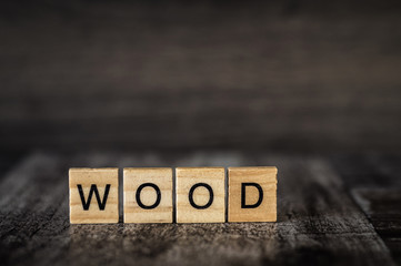 the word wood is made of bright wood cubes with black letters on a dark wooden background