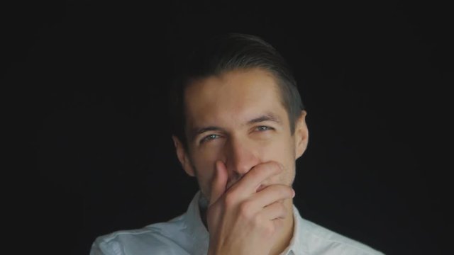 Closeup Skeptical Man standing on black background looking forward with disappointment in slowmotion. Facial emotions
