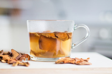 Home made hot drink from dried apples in a glass cup, white kitchen interior