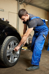 Fototapeta na wymiar A professional of the automotive car service is tightening the bolts in a tire.