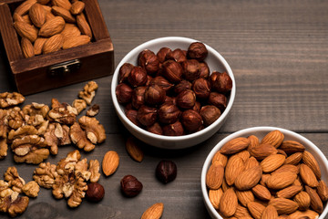 Two white cups with nuts, almonds, hazelnuts, walnut and a wooden box with almonds