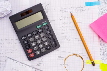 Education and Science concept. Handheld Calculator, Pencil, Ruler over Sheet of Paper with Mathematical Formulas.