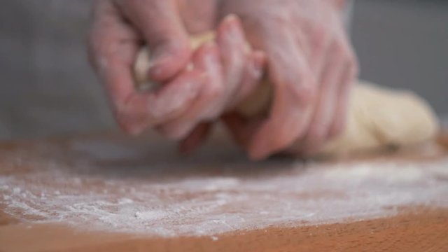 Baker Kneading Dough in Flour on the Table Near Kneading Dough on the Kitchen Table