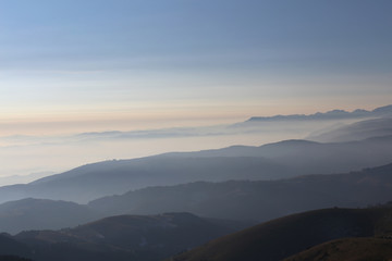 Naklejka na ściany i meble Mountains at sunrise surrounded by fog