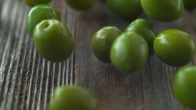 Green olives falling and rolling on a table. Shot with high speed camera, phantom flex 4K. Slow Motion.