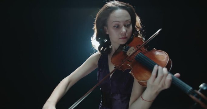 a talented girl violinist performs at her first solo concert, stage light, dark background