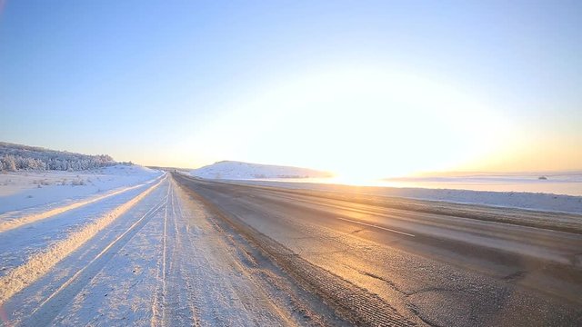 Winter road through snowy fields and forests