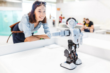 A female student controls the work of an intelligent humanoid robot